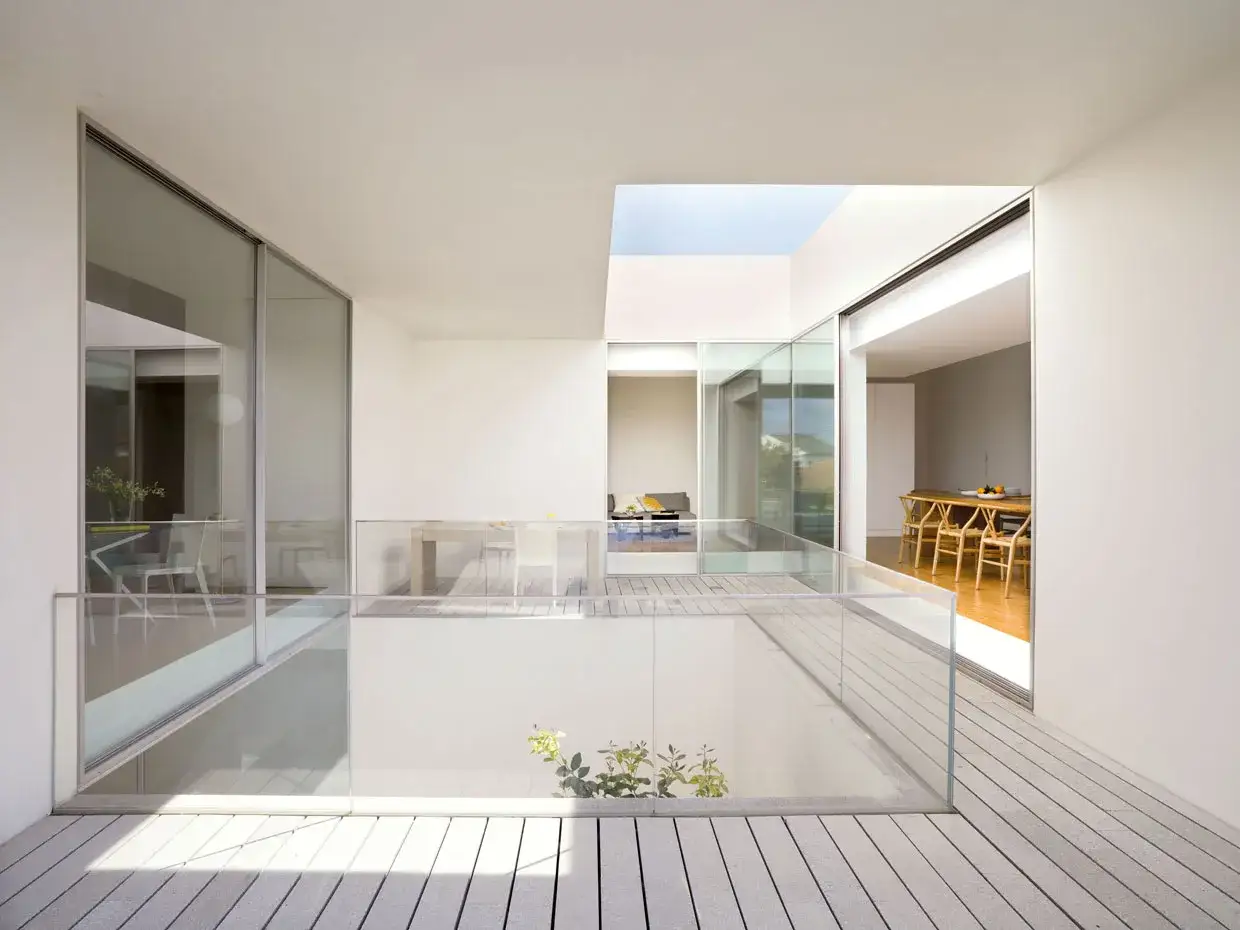 Un patio moderno con techo acristalado, ideal para como techar un patio sin perder luz. Se ve un comedor y sala de estar.