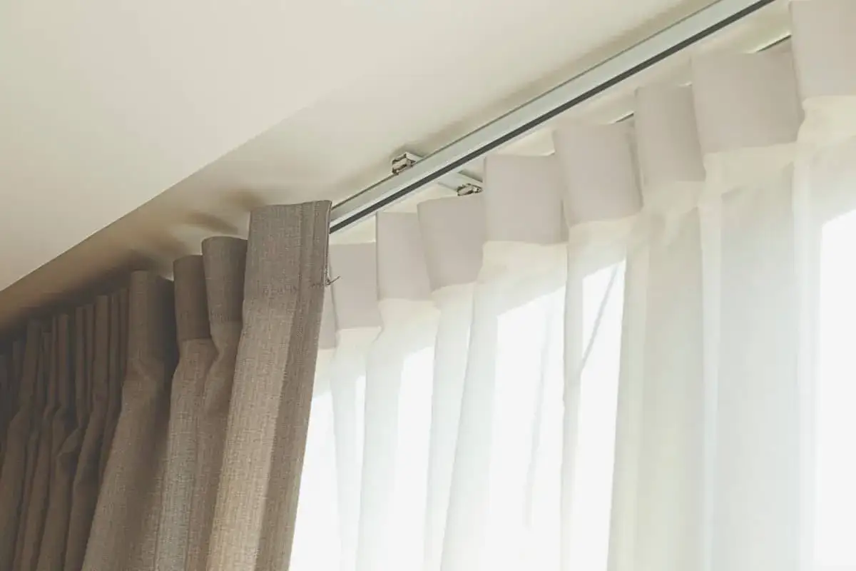 Detalle de rieles para cortinas, mostrando diferentes tipos de tela y su sistema de sujeción al techo.