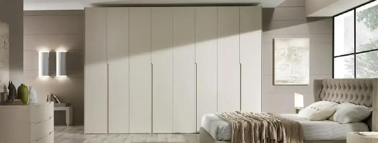 Dormitorio moderno con armarios a medida, cama con cabecero tapizado y gran ventanal.