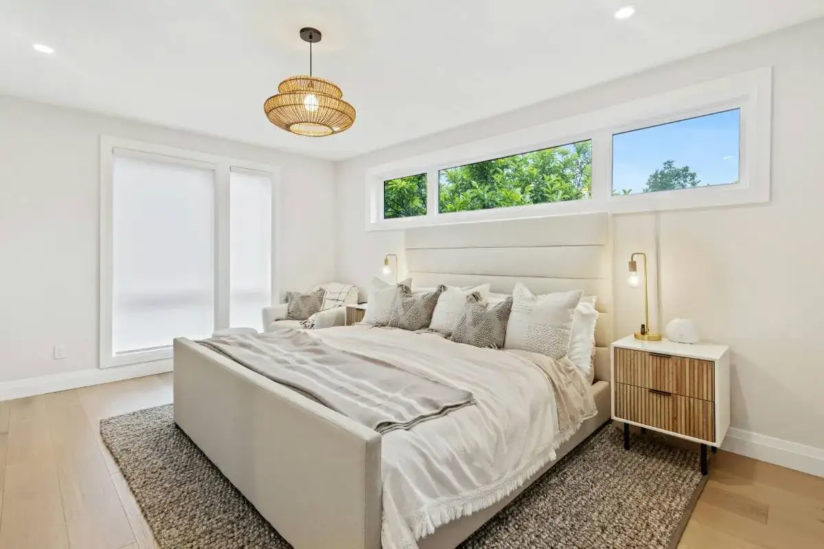 Acogedor dormitorio con cama grande y ventana en el cabecero que ilumina la estancia con luz natural.
