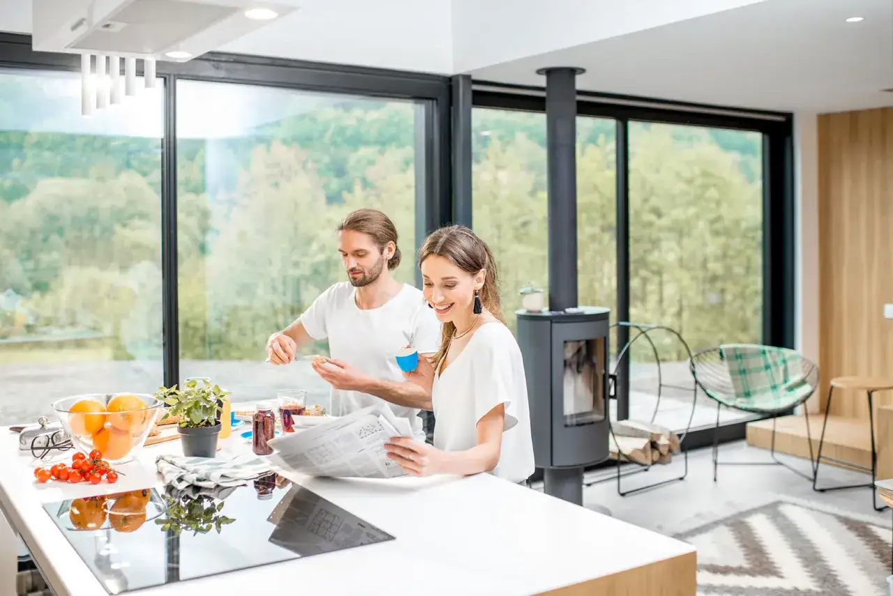 Pareja desayunando en cocina moderna con grandes ventanales, mostrando las ventajas del vidrio para disfrutar del paisaje.
