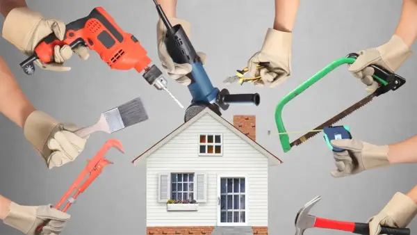 Manos con guantes sostienen herramientas de construcción alrededor de una casa. ¡Calcula tu reforma casa precio!
