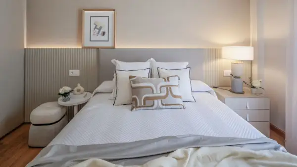 Elegantes ideas de habitaciones de matrimonio con cama blanca, cojines decorativos y mesita de noche con lámpara.