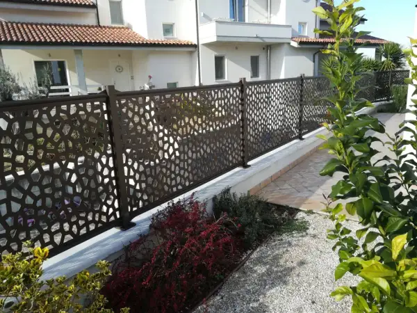 Modern metal fence with geometric cutouts, offering privacy and style. Perfect for **ideas ocultación jardin** and creating a chic outdoor space.