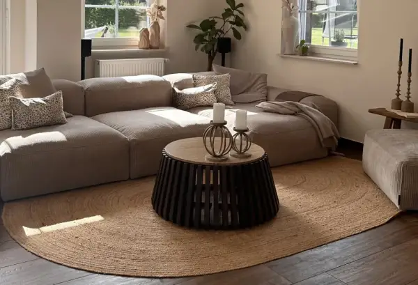 Alfombra redonda de yute, uno de los tipos de alfombras más naturales y versátiles, complementa un salón moderno con sofá modular y mesa de centro.