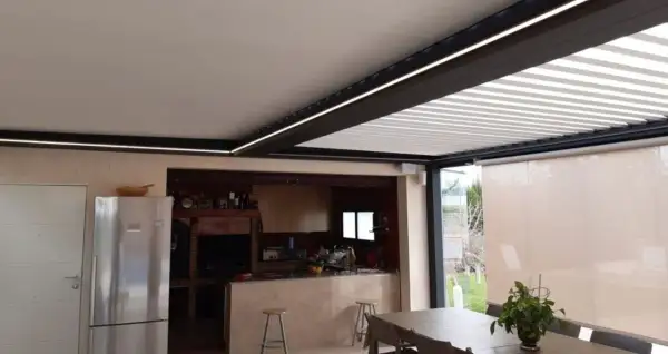 Un moderno patio de luces con normativa de iluminación LED integrada, que ilumina una cocina exterior y zona de comedor.